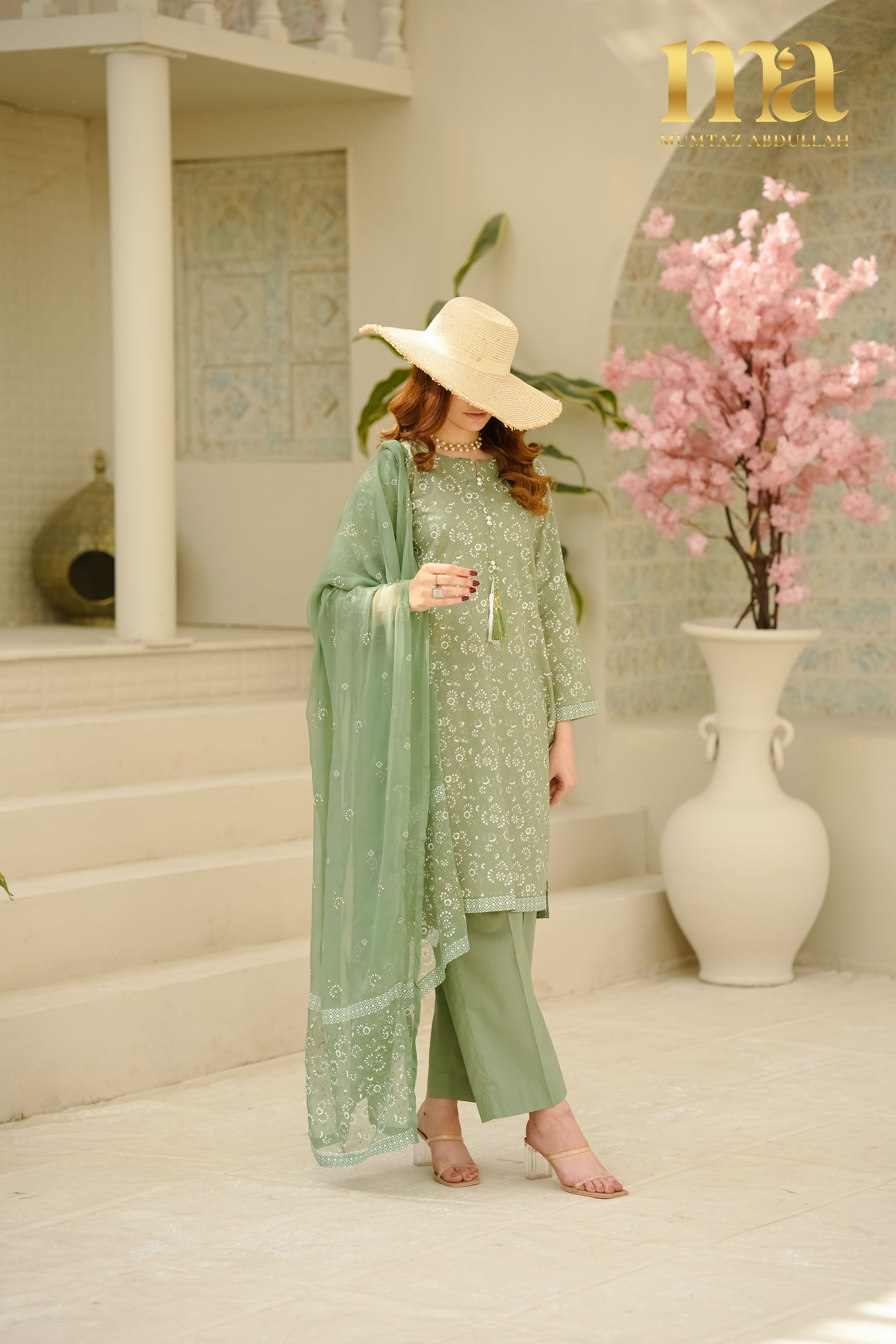 Woman wearing elegant green traditional outfit in a styled indoor setting